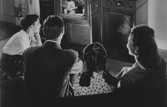 Black and white photo of a mid 20th century family gathered around a TV set
