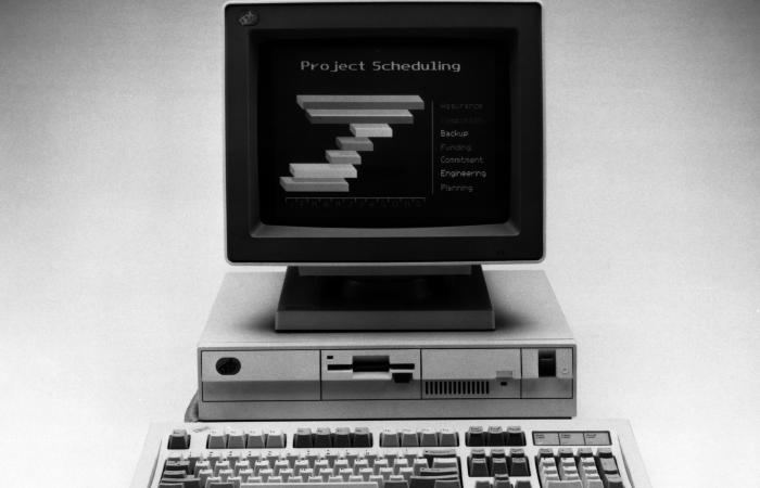 A black and white photograph of a vintage desktop computer. It has CRT monitor displaying several lines of text.