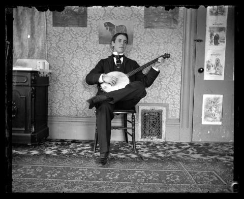 Black and white image of a young man playing a banjo