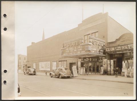 Black and white photograph of a 1930s movie theatre on a commercial street.