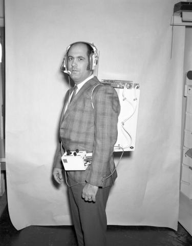 Man in a plaid suit modeling a space communication system prototype.