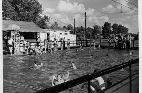 Black and white photograph of a pool full of young people.