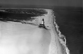 Black and white aerial photograph of the Cape Henlopen Lighthouse and surrounding landscape.