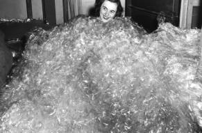 Black and white image of a woman buried up to her neck in crumpled cellophane.