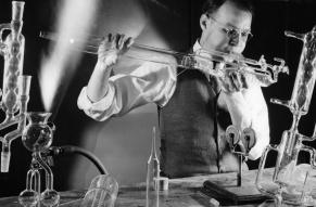 Black and white image of a glass blower making chemical laboratory glassware