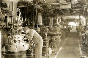 Black and white photograph of a man working in a machine shop.