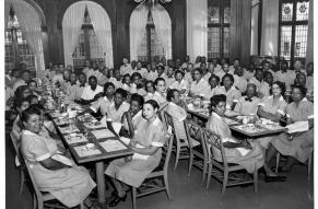 Black and white photograph of Black workers seated in the a dining room; all are wearing uniforms