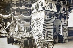 Large architectural arch covered in various guns, inside a large convention center.