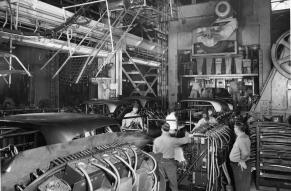 Black and white image of workers assembling automobiles