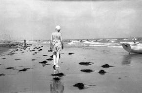 Black and white image of a woman walking on beach with back to camera at Ventnor, New Jersey, or Rehoboth, Delaware