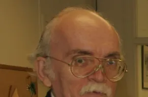 A Caucasian man with a mustache and glasses looking at the camera.
