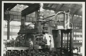 Black and white photograph from inside a Bethlehem Steel factory, showing workers and large industrial shearing equipment.