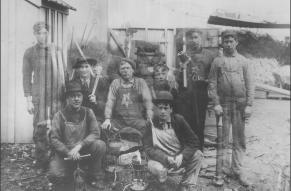 Black and white photograph of a group of workers - some of the men appear transparent as a result of an error in the photographic process.