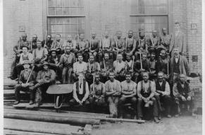 Black and white group photograph of a large number of men in work clothes.