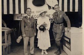 Black and white image of two men and a woman standing in front of a stratosphere gondola balloon.