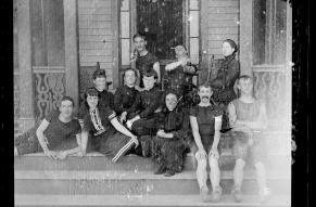 Black and white glass negative showing a group of young people in 1880s beachwear seated on porch steps.