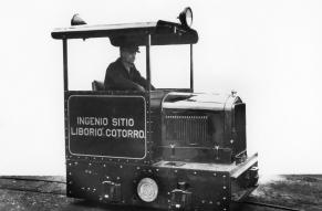 Black and white image of a man seated in a very small locomotive.