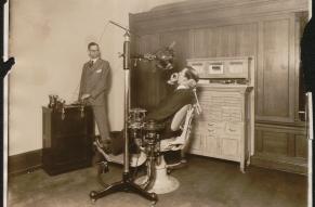 Black and white photograph showing a demonstration of dental x-ray equipment.