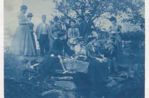 Cyanotype photograph of a group of people in an outdoors setting.