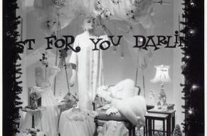 Black and white photograph of a Christmas themed store window display with the phrase 'Just for you darling' painted on the window.