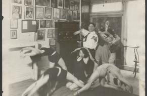 Black and white photograph of a man operating a radio console while surrounded by dancers in motion.
