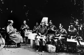 Black and white photograph of a group of seated women  taping and sealing tin containers for rings for 3-inch Stokes Trench Mortar at DuPont Co. Brandywine Mills