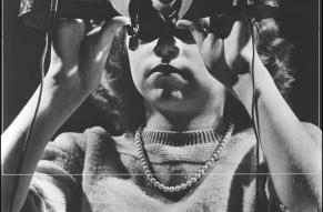 Black and white image of a young woman holding a strange object up to her eyes.