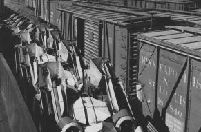 Black and white photograph of John Deere corn shuckers loaded on freight cars 