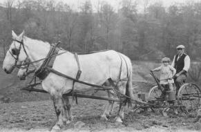 Black and white photograph of Howard Seal and his granddaughter, Eleanor Seal, planting corn with horse-drawn planter.
