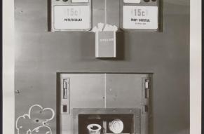 Close up black and white photograph of a food vending machine offering potato salad and fruit cocktail in cherry jello.