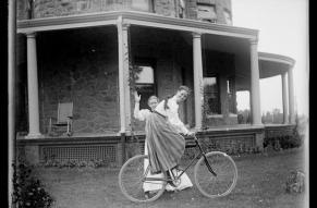 Two women on a lawn with a bicycle in front of St. Amour, a du Pont family home.