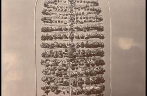 Black and white photo of a bell jar display containing a large number of small ornaments carved from nutshells.