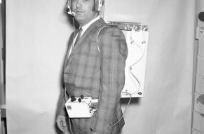 Man in a plaid suit modeling a space communication system prototype.